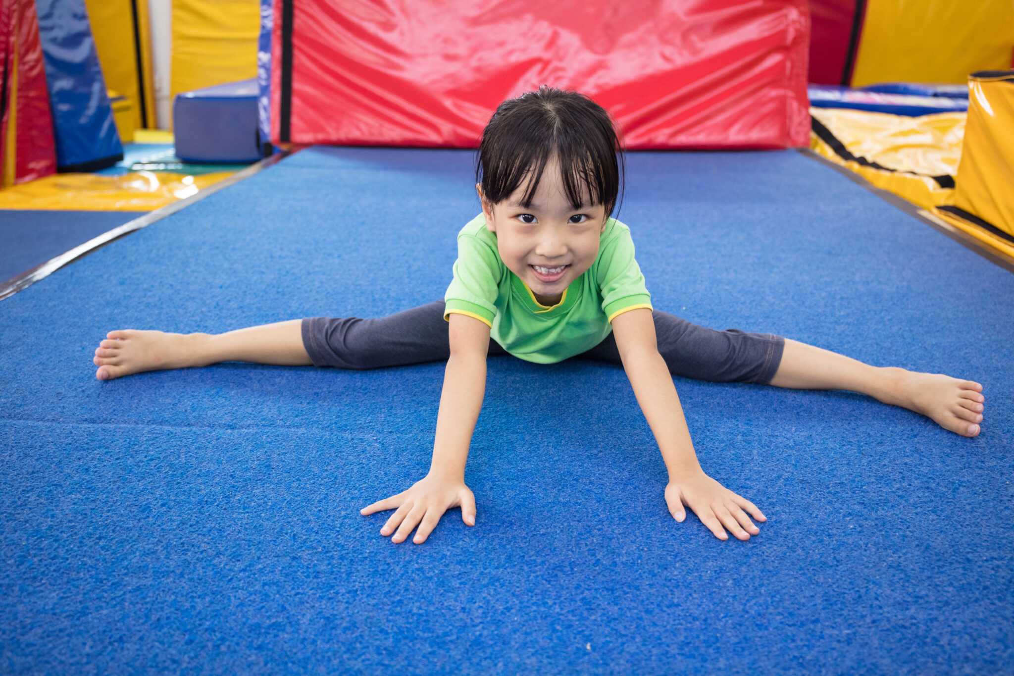 A little girl is doing a split on the floor