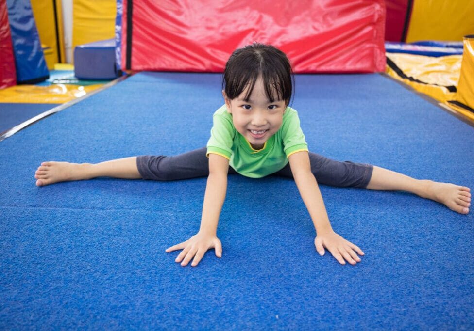 A little girl is doing a split on the floor